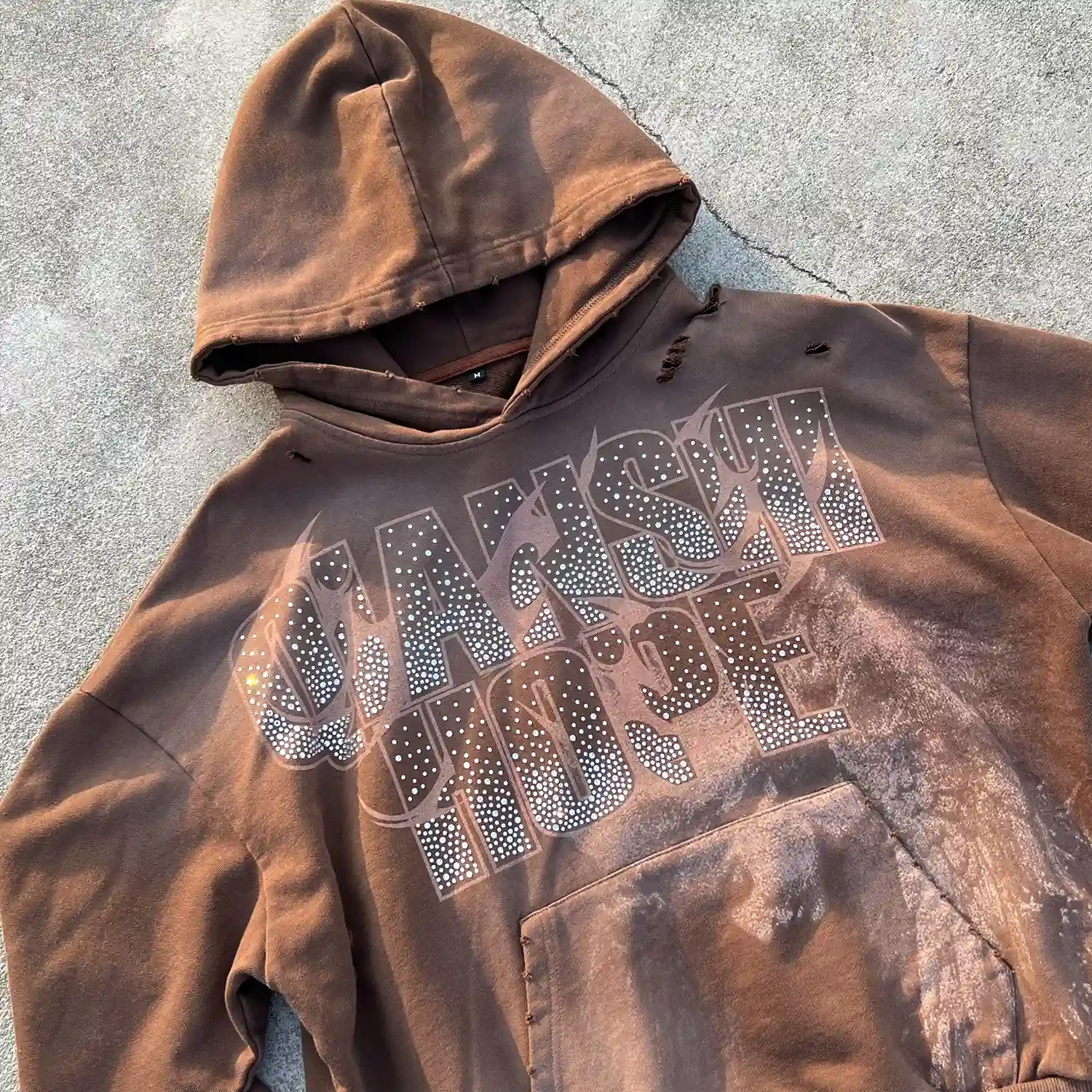 Close-up of customizable hot-fix rhinestone typography graphic on vintage brown streetwear