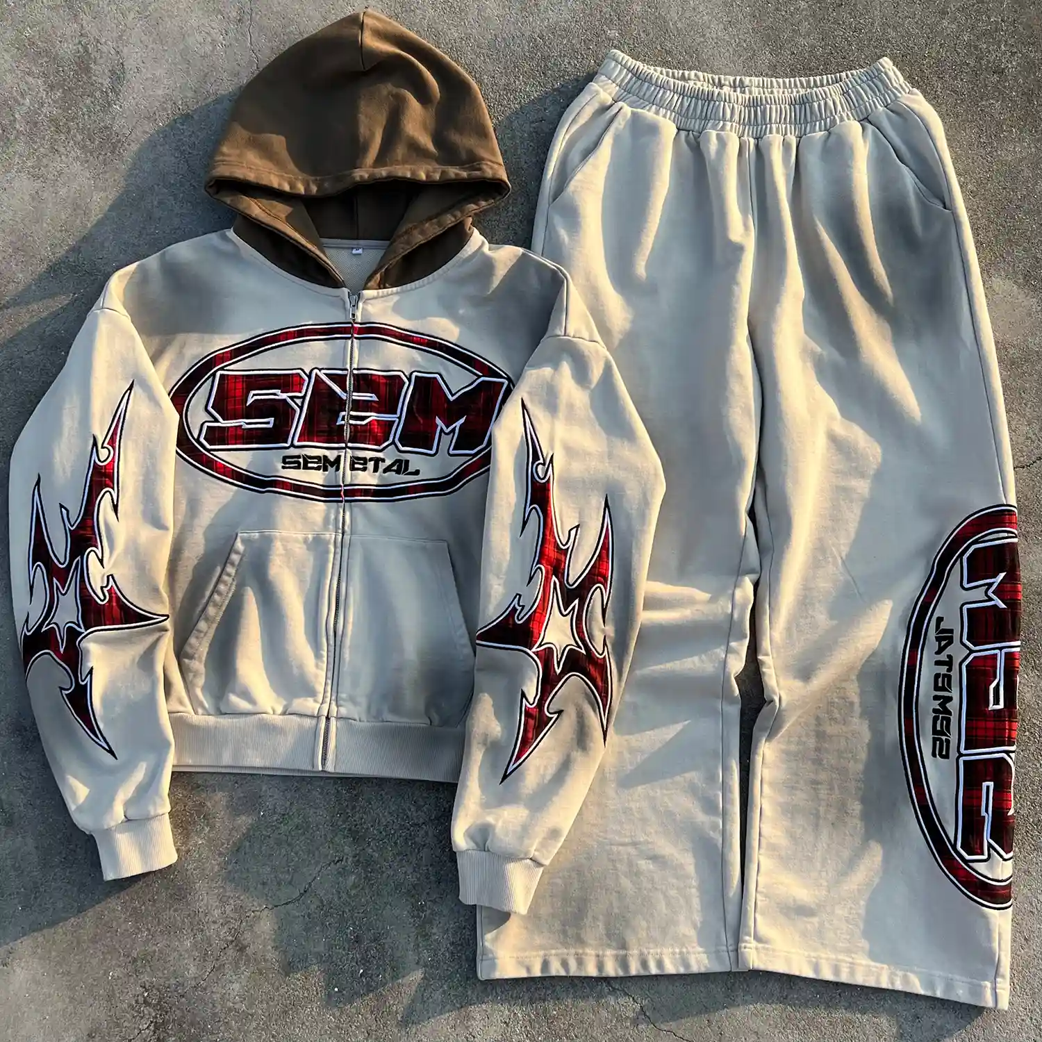 Front view of wholesale Y2K streetwear tracksuit in vintage wash beige featuring red plaid appliqué on hoodie and pants