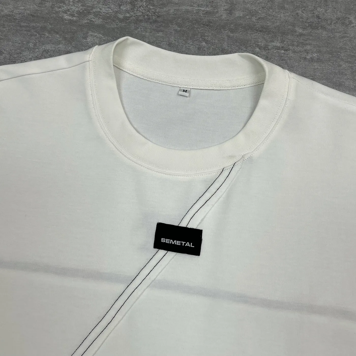 Close-up collar detail of the cut and sew t-shirt OEM sample featuring chest woven label patch