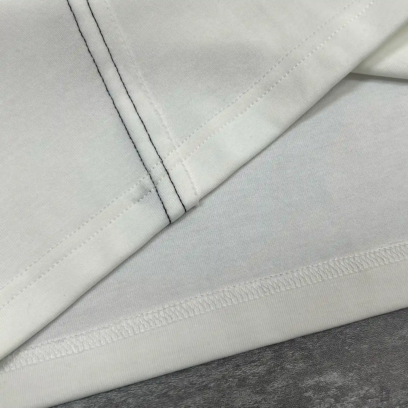 Macro detail of the double-needle diagonal stitching and hem on the premium streetwear manufacturer tee