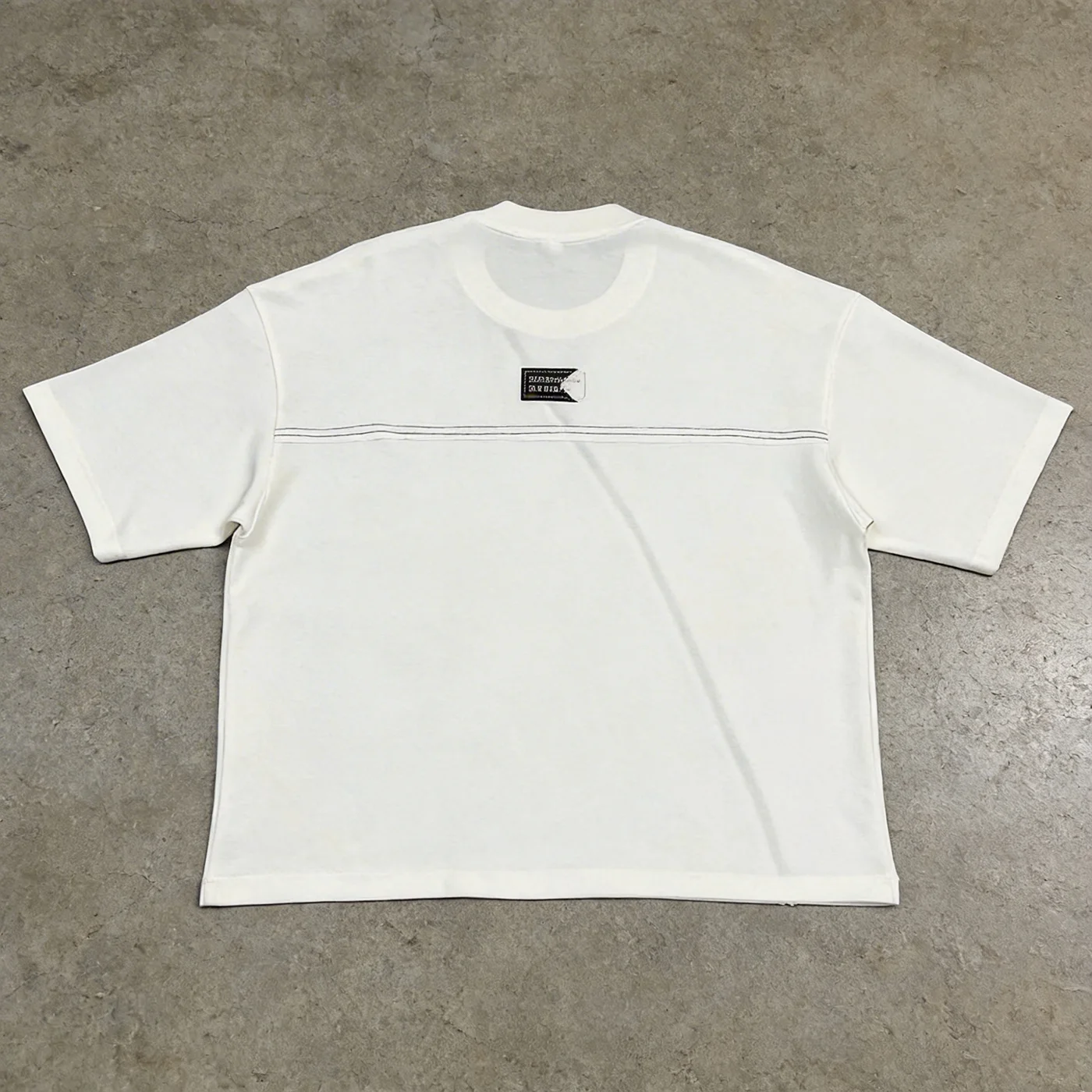 Flat lay back view of the custom woven label oversized t-shirt highlighting horizontal back seam and patch