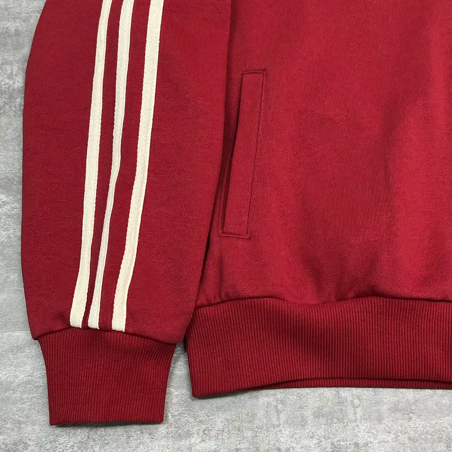 Close-up of custom track jacket raglan sleeve featuring contrasting stripes and side pocket.