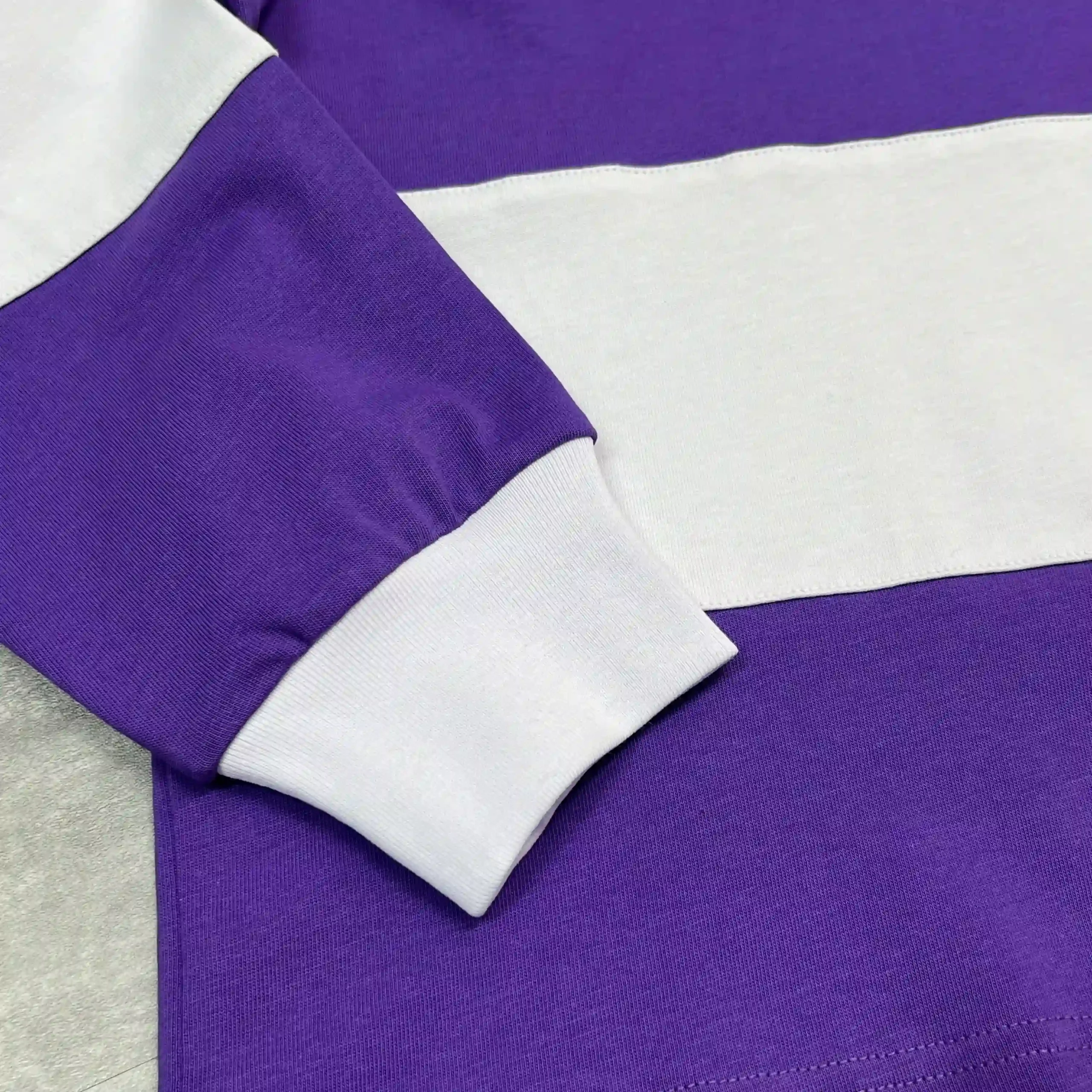 Detail shot of ribbed cuff and cut-and-sew wide stripe construction on custom striped polo shirt.