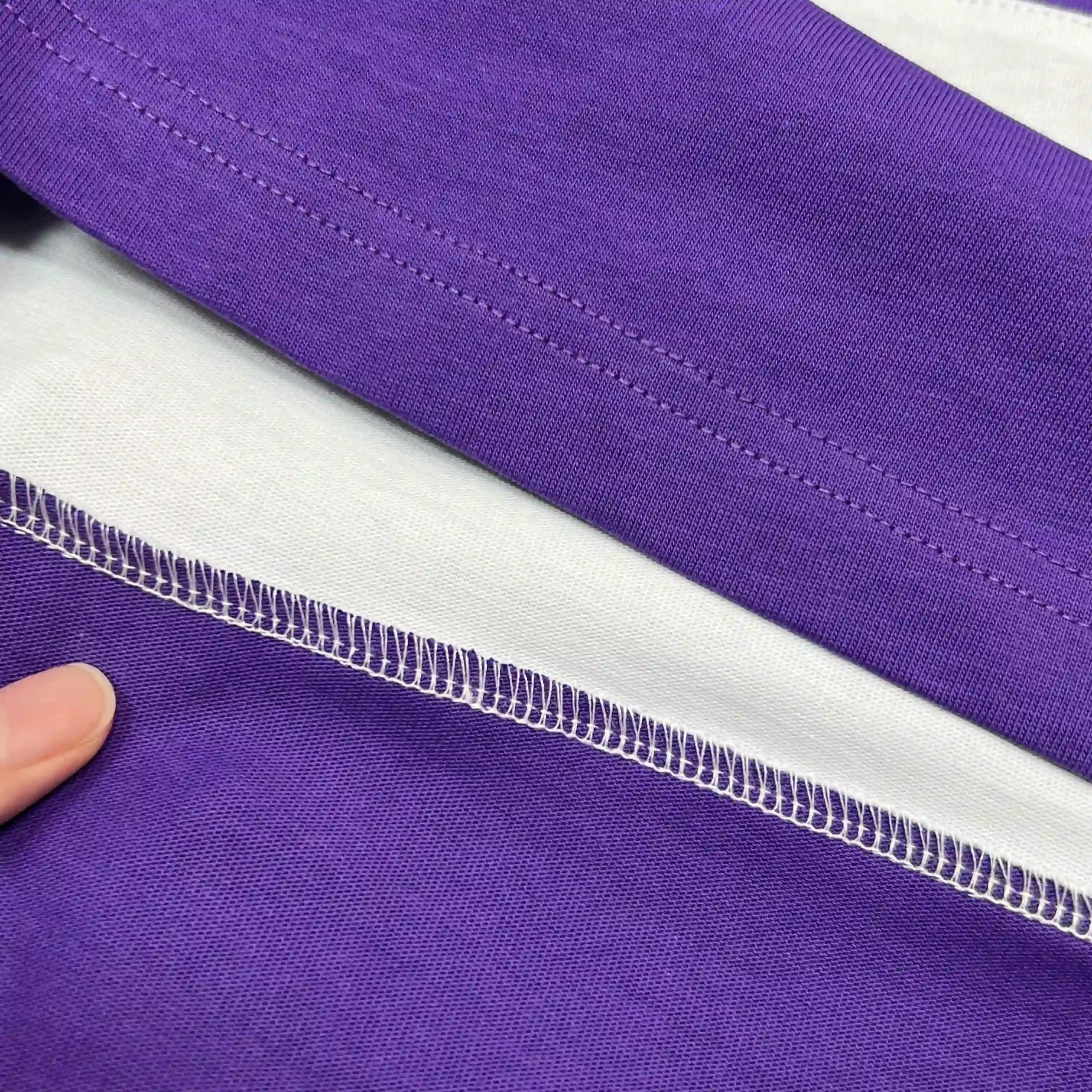 Macro view of interior overlock stitching on 250GSM combed cotton jersey fabric.