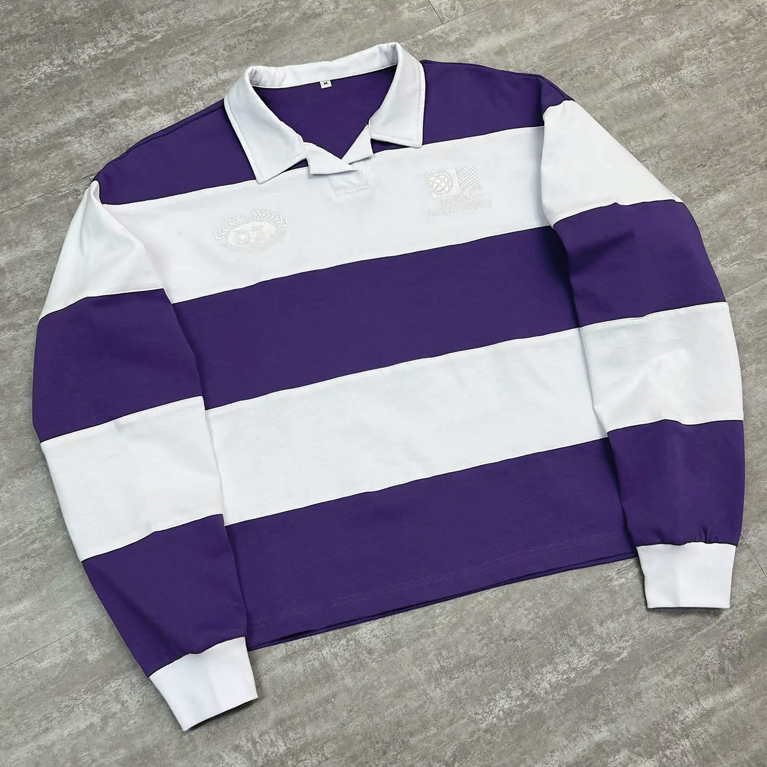 Angled flat lay highlighting the drop shoulder fit of the custom striped polo shirt.