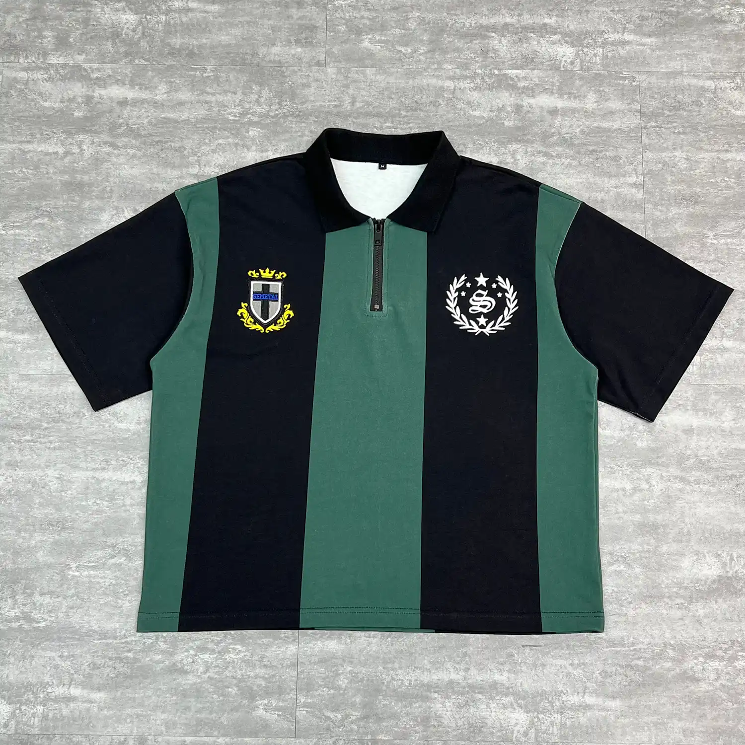 Front flat lay of the black and green custom striped polo shirt highlighting chest embroidery.