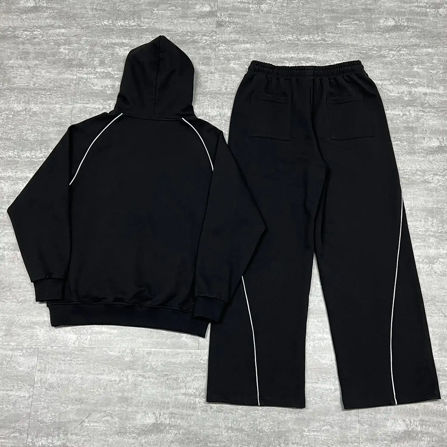 Back flat lay of the OEM streetwear tracksuit set highlighting the continuous curved piping down the pant legs.