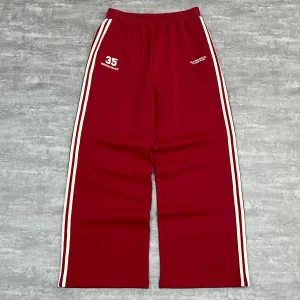 Full front view of red custom track pants with wide leg fit and vintage double side stripes.