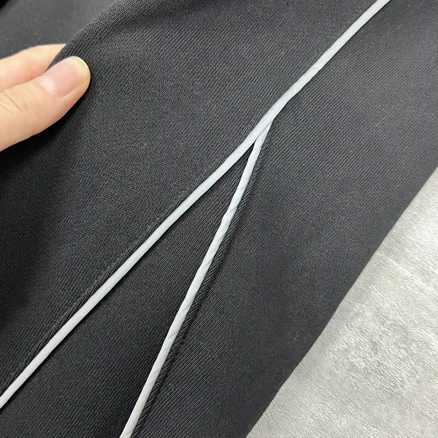 Macro detail of the precision contrast white piping embedded into the black cotton blend fabric.