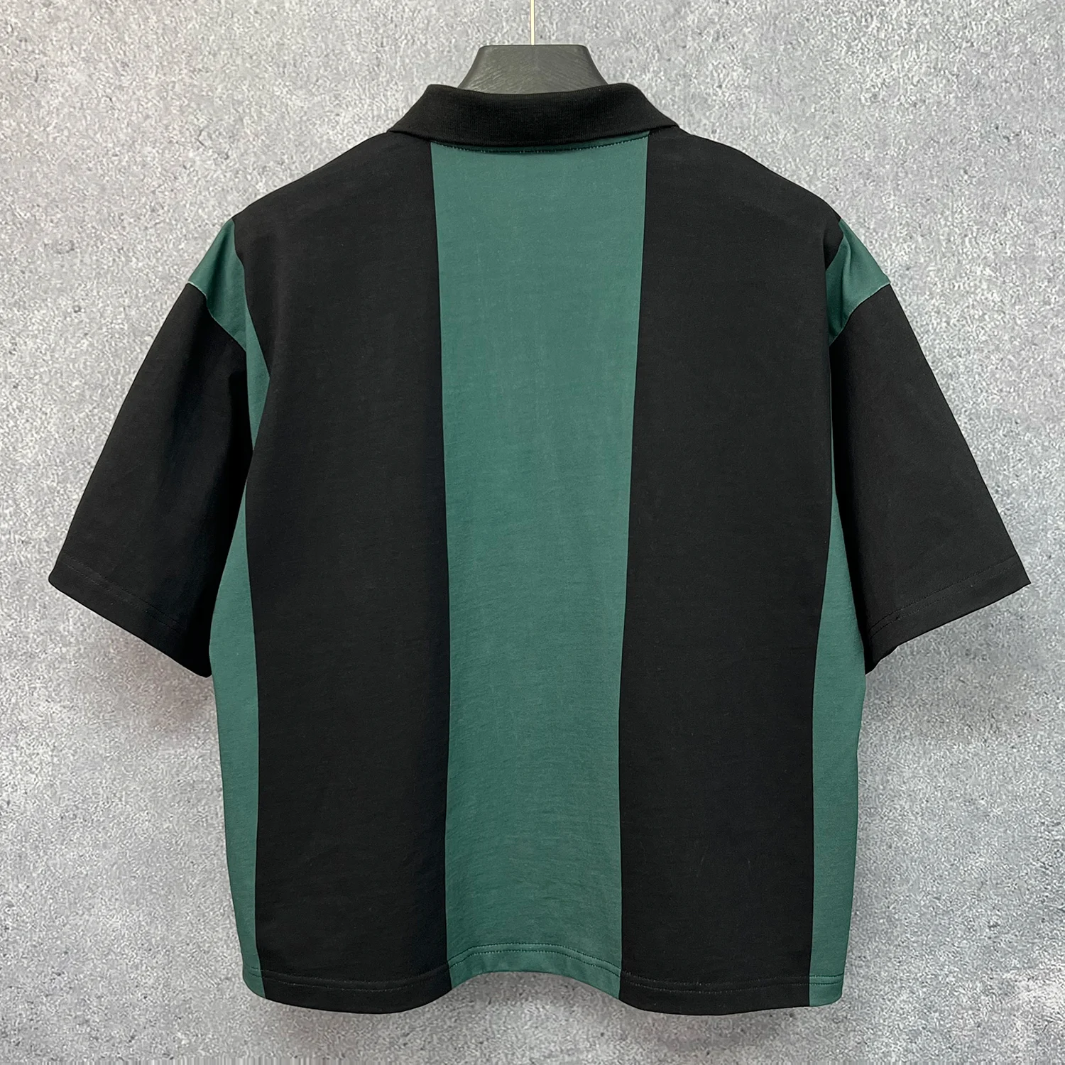 Back view of hanging vertical striped polo shirt ready for custom brand manufacturing.